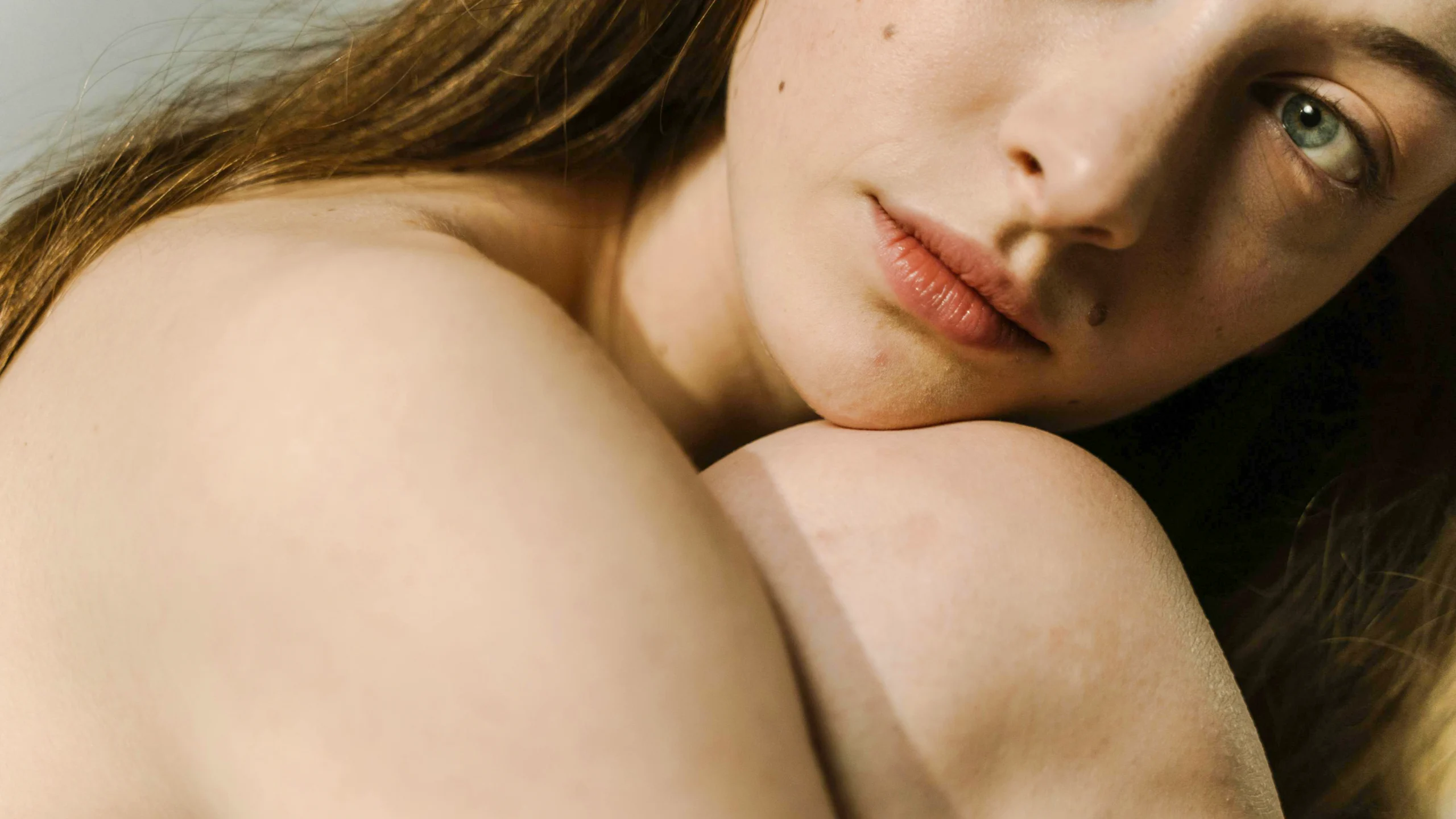 Közeli portré egy fiatal nőről, természetes smink nélkül, finom bőrtextúrával és meleg, lágy fényekben.